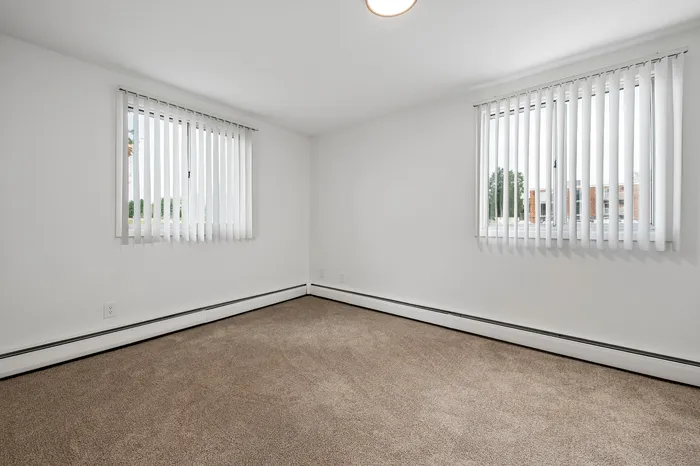 Bright and inviting room with large windows and elegant carpet flooring, ideal for a cozy living space.