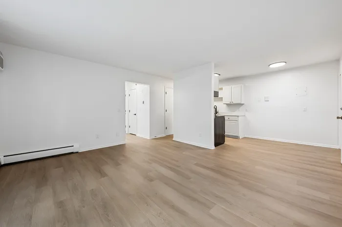Spacious open-plan living area with elegant wooden floors and a modern kitchen, perfect for stylish city living.