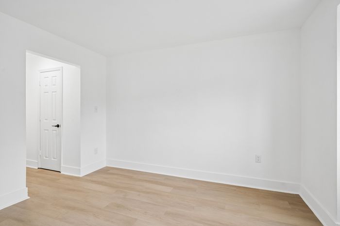Bright, modern room with elegant hardwood flooring and crisp white walls, offering versatile space for personalized design.