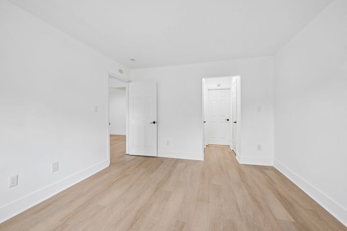 Bright and inviting room with sleek wood flooring and crisp white walls, offering a modern and spacious feel.