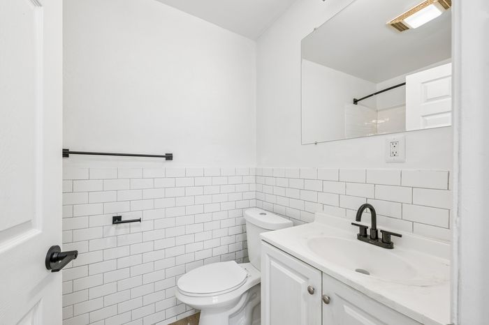Bright and modern bathroom with sleek subway tile, black fixtures, and a large mirror.
