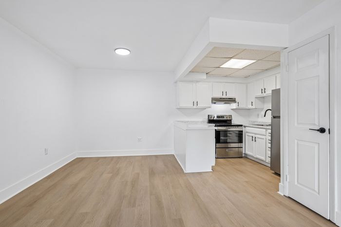 Bright and modern kitchen with sleek stainless steel appliances, open layout, and elegant light wood flooring.