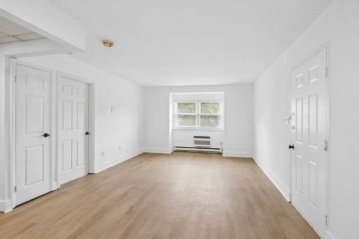 Bright and spacious living room with sleek hardwood floors and large window enhancing natural light.
