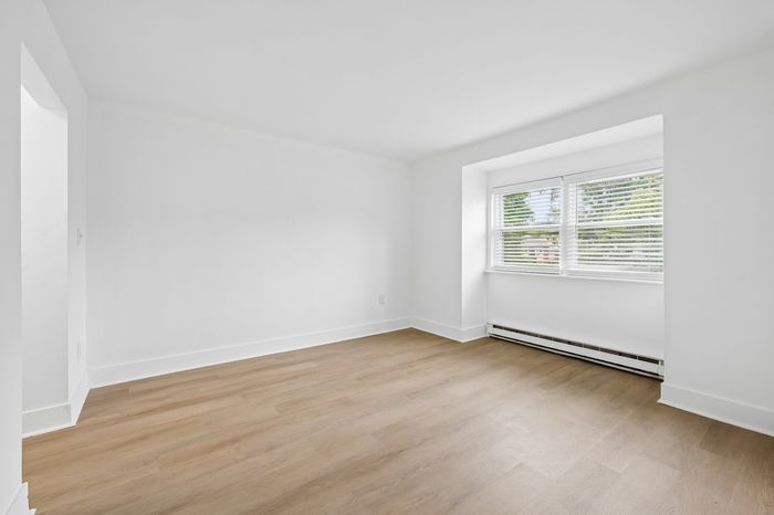 Bright and spacious room with hardwood floors and large window providing abundant natural light, perfect for versatile design possibilities.