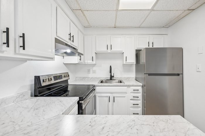Modern kitchen with sleek stainless steel appliances, elegant white cabinetry, and marble countertops.