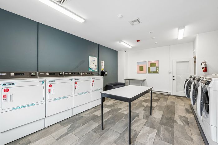 Modern laundry room equipped with multiple high-efficiency washers and dryers, offering a convenient and stylish space for residents.