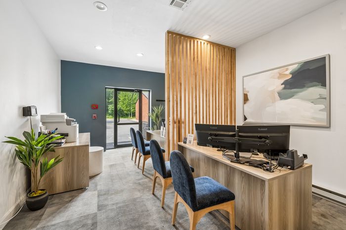 Modern office space with plush seating, sleek wooden accents, and vibrant wall art, perfect for professional meetings.