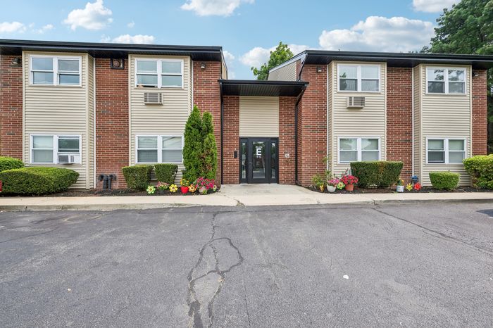 Charming brick apartment building with lush greenery and vibrant flower arrangements.