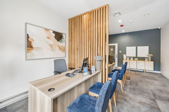 Chic and modern apartment leasing office with stylish wood accents, plush blue seating, and contemporary artwork.