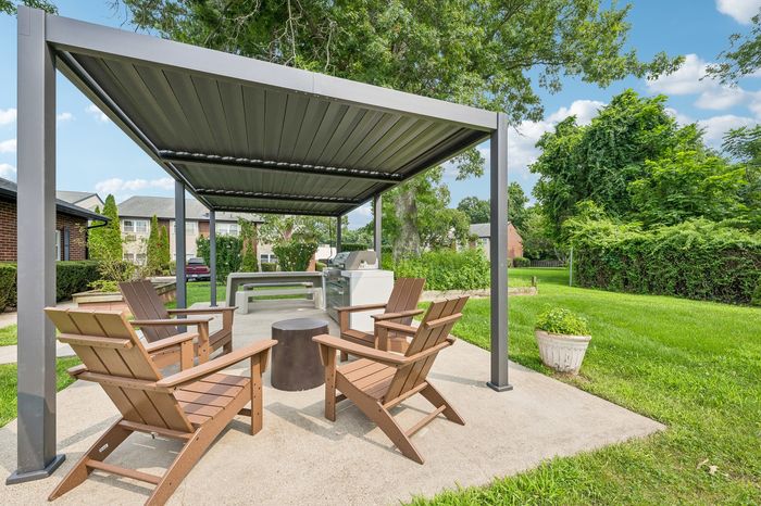 Inviting outdoor patio with modern pergola, stylish wooden seating, and lush green surroundings, perfect for relaxation and gatherings.