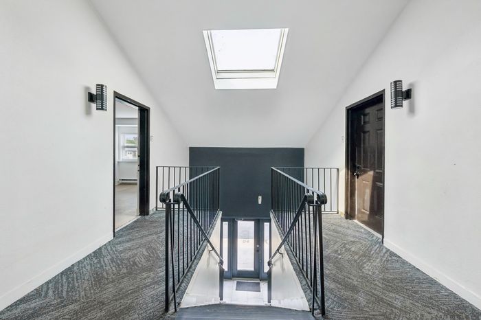 Bright and inviting hallway with skylight, modern fixtures, and clean design.