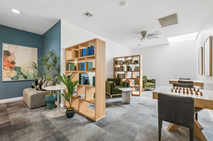 Inviting lounge area with modern bookshelves, chic seating, lush plants, and natural light, ideal for relaxation and social gatherings.