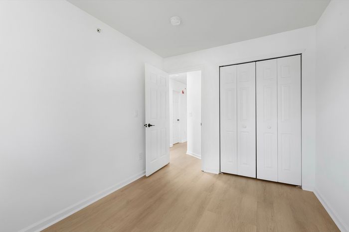 Bright and inviting room with elegant white doors, spacious closet, and sleek hardwood floors.