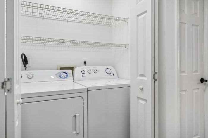 Compact laundry area with modern washer and dryer, enhanced by spacious shelving for storage solutions.
