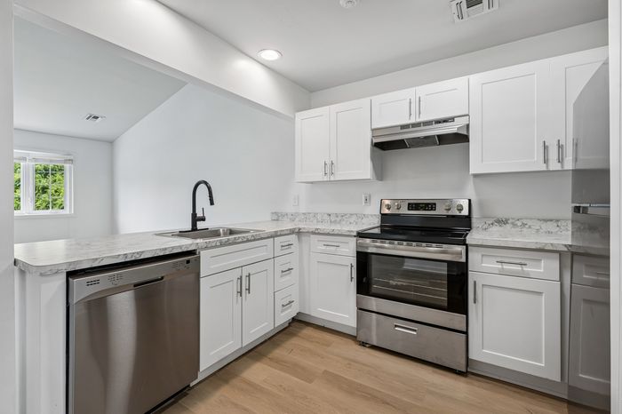 Modern kitchen with sleek stainless steel appliances, white cabinetry, and elegant marble countertops offering a bright, inviting space.