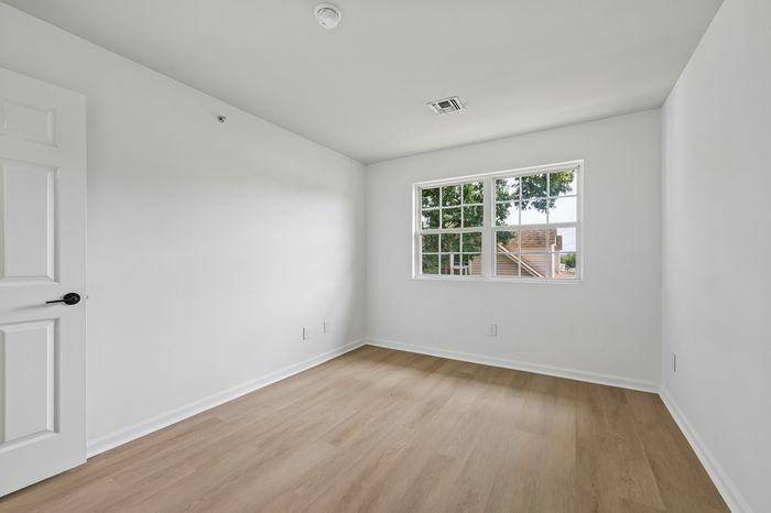 Bright and airy room with elegant hardwood floors, large window providing scenic views, and freshly painted white walls.