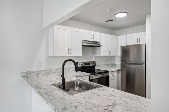 Modern kitchen with sleek stainless steel appliances, elegant marble countertops, and crisp white cabinetry.