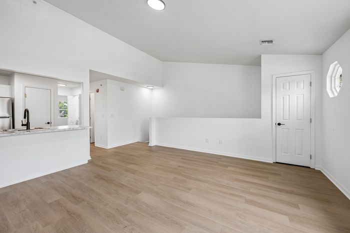 Modern apartment interior showcasing a sleek open floor plan with wood flooring, a stylish kitchen with marble countertops, and abundant natural light.