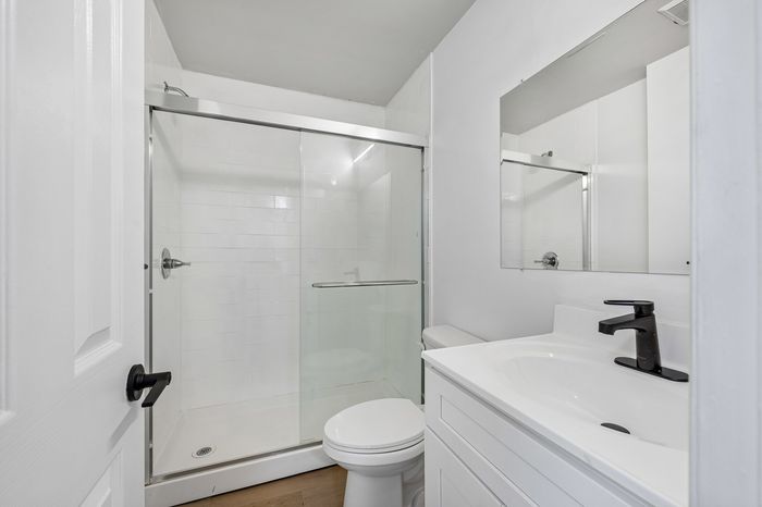 Modern bathroom with sleek glass shower, elegant white vanity, and contemporary fixtures.