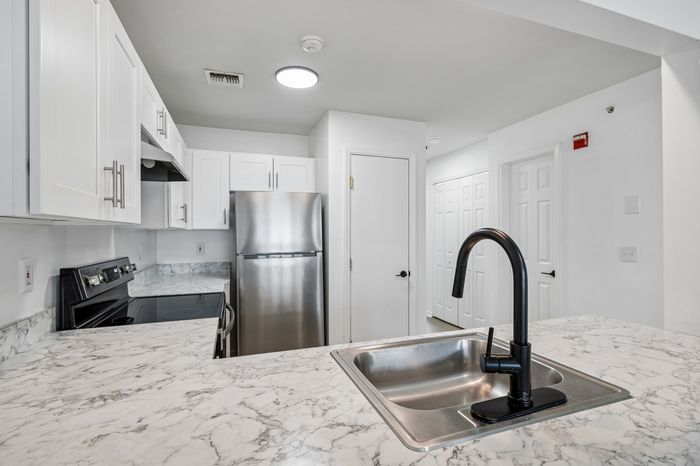Contemporary kitchen with elegant marble countertops, sleek stainless steel appliances, and stylish black faucet.