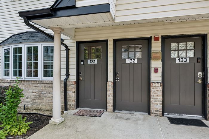 Charming apartment exterior featuring stylish dual-tone design, large bay window, and welcoming front entrances.