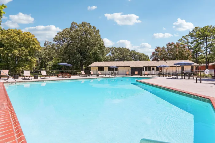 Inviting swimming pool with lounge chairs and umbrellas surrounded by lush greenery, perfect for relaxation.