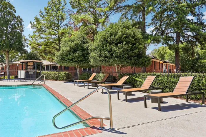 Inviting outdoor pool area surrounded by lush greenery and modern lounge chairs, ideal for relaxation and leisure.