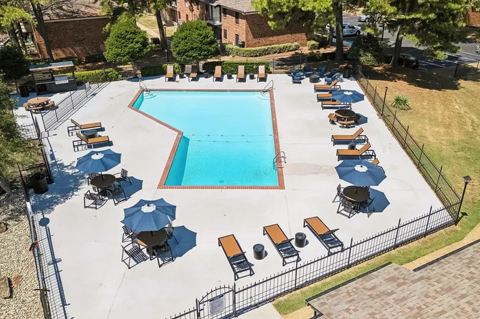 Inviting outdoor pool surrounded by comfortable lounge chairs and shaded tables, perfect for relaxing and entertaining.