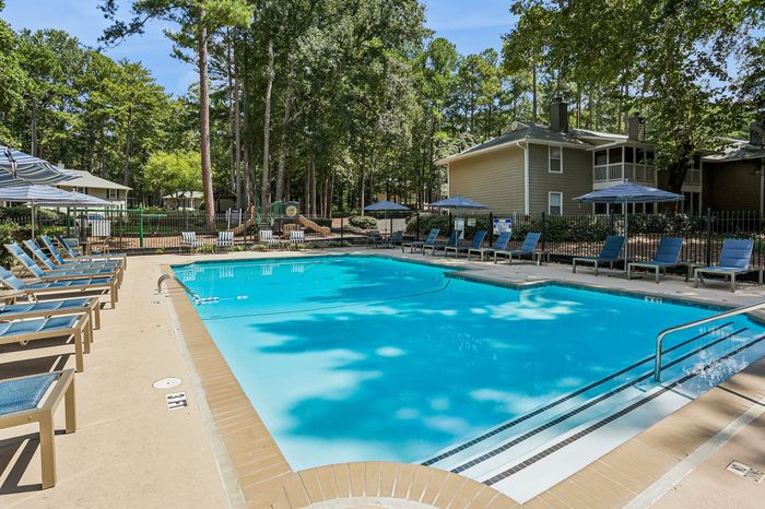 Inviting outdoor pool area surrounded by lush greenery and comfortable lounge chairs, perfect for relaxation and leisurely swims.