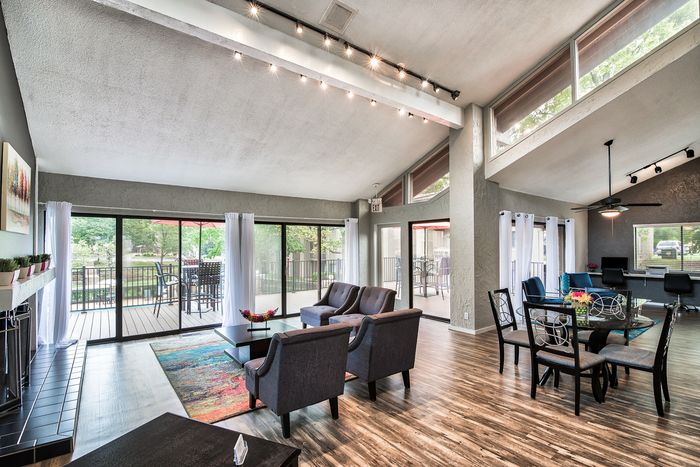Bright and spacious living area with modern decor, featuring stylish seating, wood flooring, and large windows opening to a balcony with a serene view.