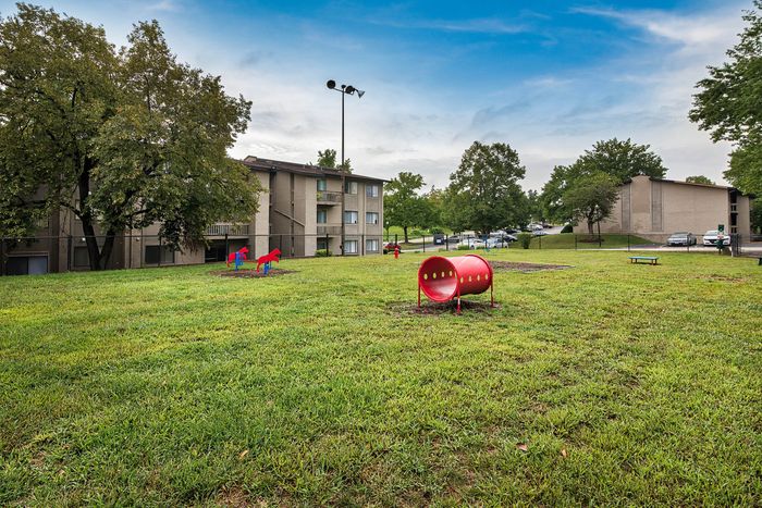 Inviting apartment complex with lush green spaces and playful outdoor amenities perfect for families.