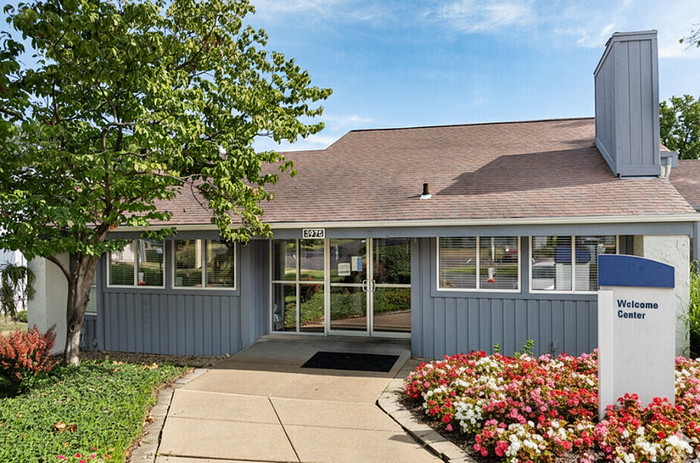 Welcoming entrance with lush greenery and vibrant flowers leading to a charming center, perfect for first impressions.