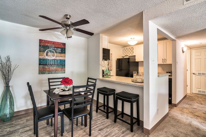 Contemporary dining area with elegant decor adjacent to a modern kitchen, featuring stylish bar stools and a chic open design.