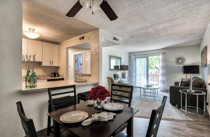Inviting open-concept living space featuring a modern kitchen with a breakfast bar, elegant dining area, and cozy living room with natural light from large windows.