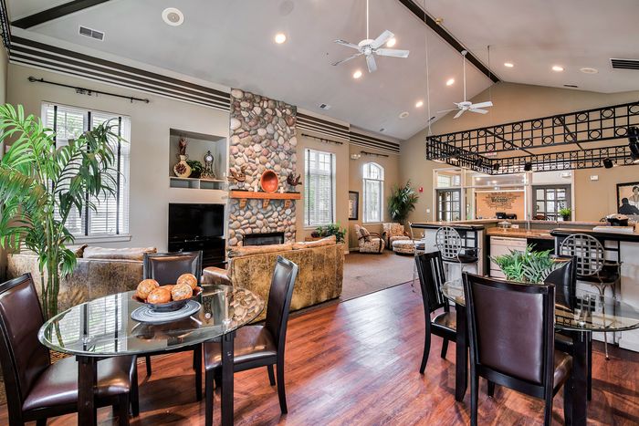 Luxurious open-concept living space featuring a cozy stone fireplace, elegant dining area, and modern kitchen with stylish decor.