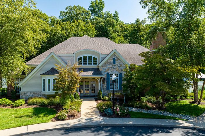 Charming suburban home with stone facade, lush landscaping, and welcoming front porch.