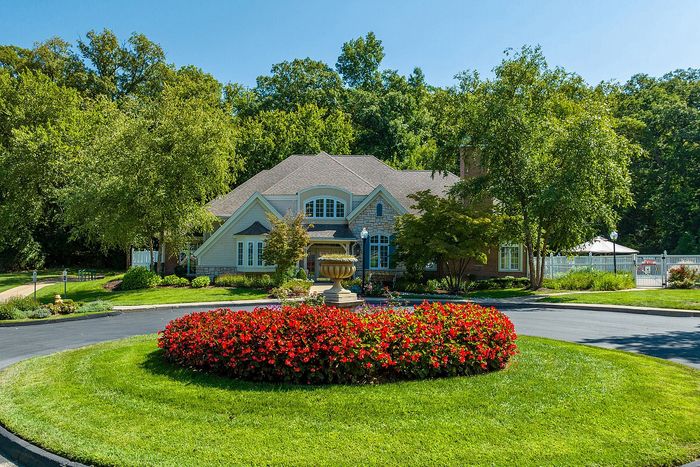 Charming home with a lush garden and vibrant flowerbed set against a backdrop of mature trees, offering a serene and picturesque retreat.