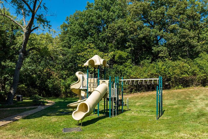Enchanting playground with slides and climbing structures nestled in a lush green park setting.