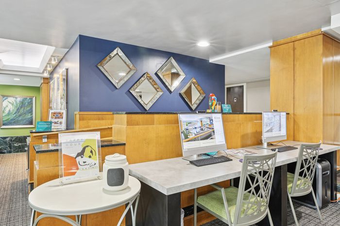 Modern apartment lobby with elegant decor, mirrors, and computer workstations.