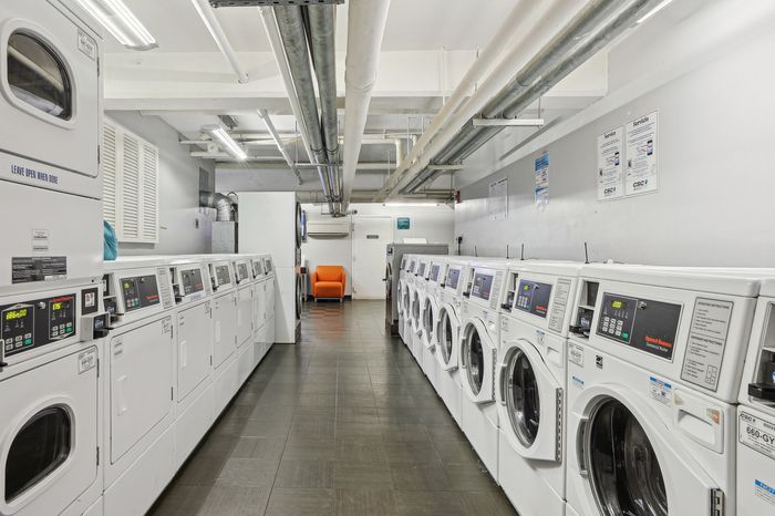 Modern laundry room with rows of washing machines and dryers, featuring contemporary design and bright lighting for an efficient laundry experience.