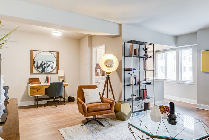 Chic apartment interior with a cozy work-from-home setup, modern leather chair, stylish shelving, and abundant natural light.