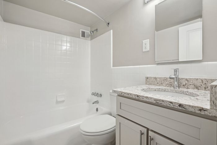 Modern bathroom featuring sleek marble countertop, pristine white bathtub, and elegant fixtures for a contemporary feel.
