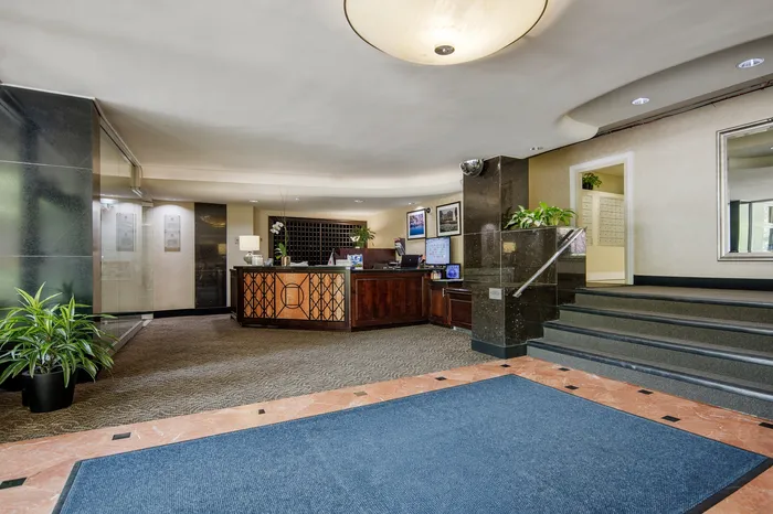 Elegant apartment lobby featuring a stylish reception desk, modern decor, and lush green plants.