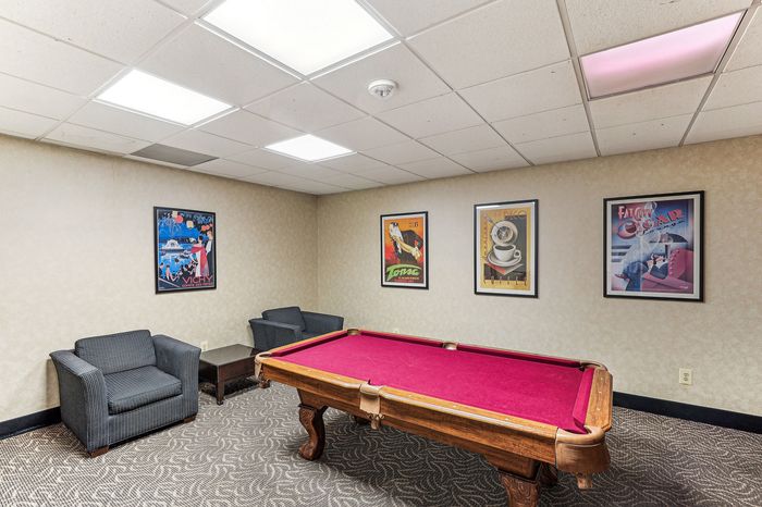 Chic lounge area featuring a vibrant red pool table, cozy seating, and artistic wall decor, perfect for entertainment and relaxation.