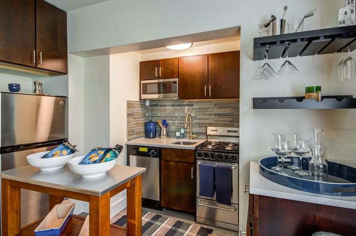 Modern kitchenette featuring stainless steel appliances, chic tile backsplash, and elegant wooden cabinets, ideal for contemporary living.