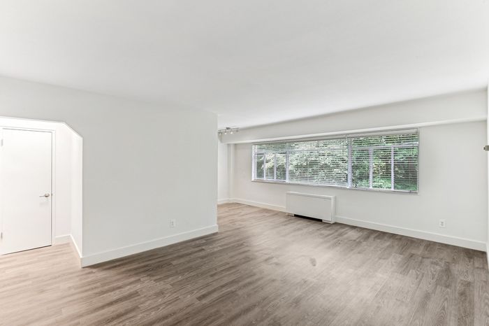 Bright and airy living space with elegant hardwood flooring, large window offering natural light and serene views.