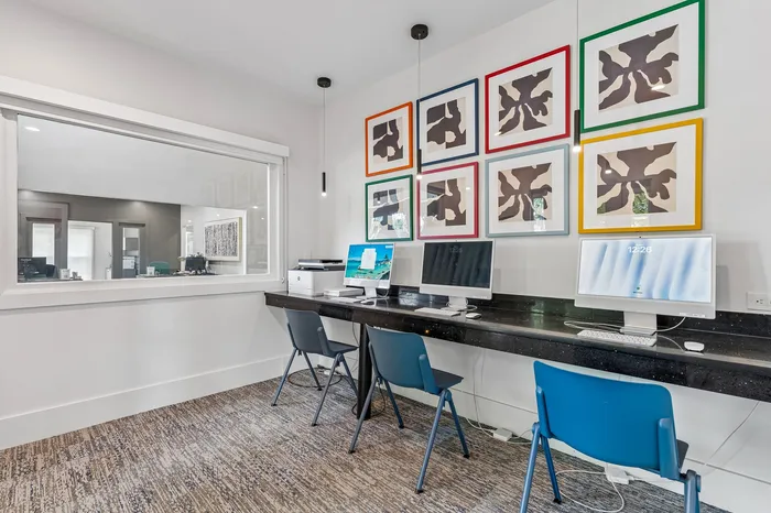 Modern home office space with dual computer workstations, sleek black countertop, and vibrant abstract artwork on the wall.