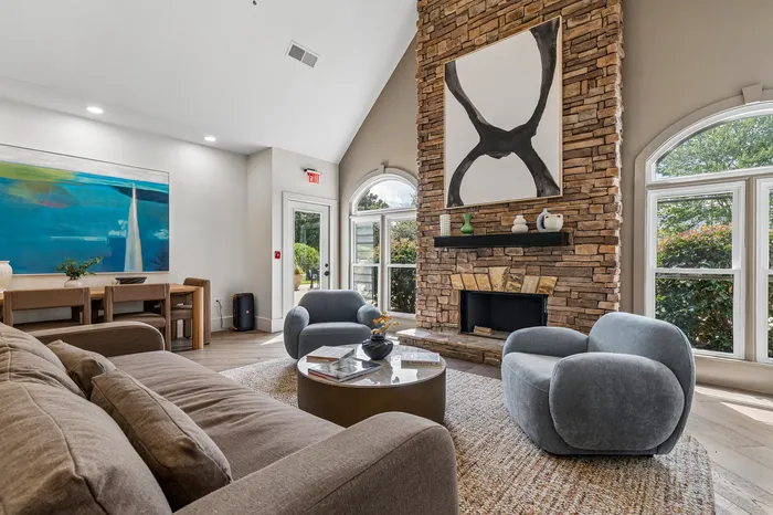Luxurious living room with a modern stone fireplace, elegant seating, and large windows inviting natural light.