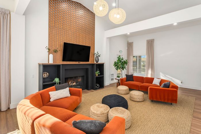 Inviting living room with vibrant orange sofas, modern accents, and a cozy fireplace, perfect for stylish relaxation.