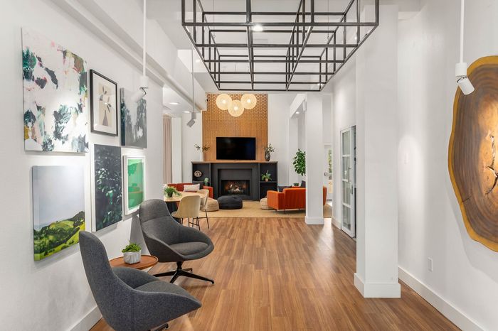 Modern, inviting living area showcasing elegant artwork, cozy seating with vibrant orange accents, and a sleek fireplace, perfect for relaxation and entertainment.
